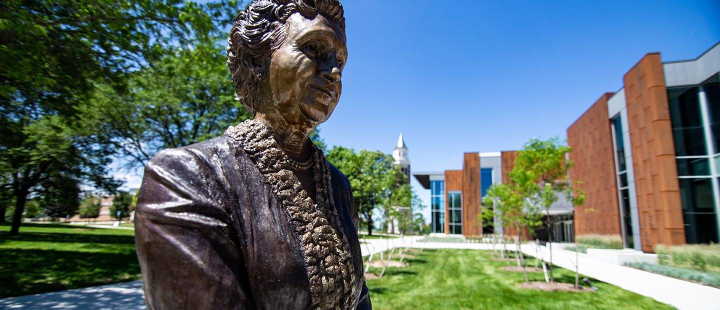 A bronze statue of a woman outside of a building on Oakland University's campus.